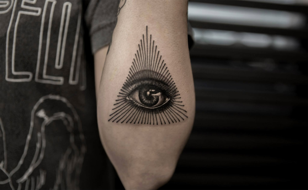 A stunning geometric illuminati eye tattoo meaning design on a forearm representing vigilance and strategic focus.